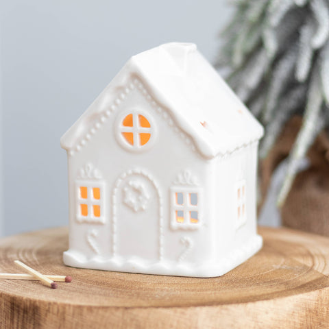 White ceramic gingerbread house tealight holder with warm glow